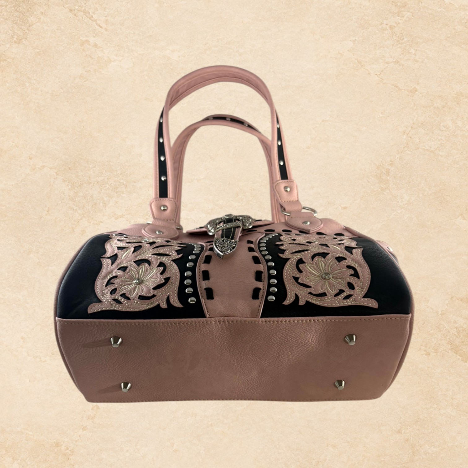 Blush pink and black purse with floral detailing, silver-tone studs, decorative stitching, and an ornate buckle accent.