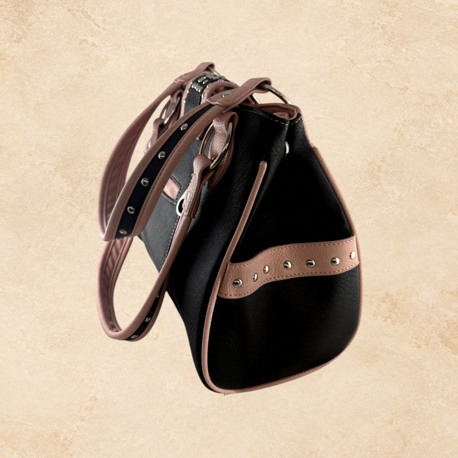Blush pink and black purse with floral detailing, silver-tone studs, decorative stitching, and an ornate buckle accent.