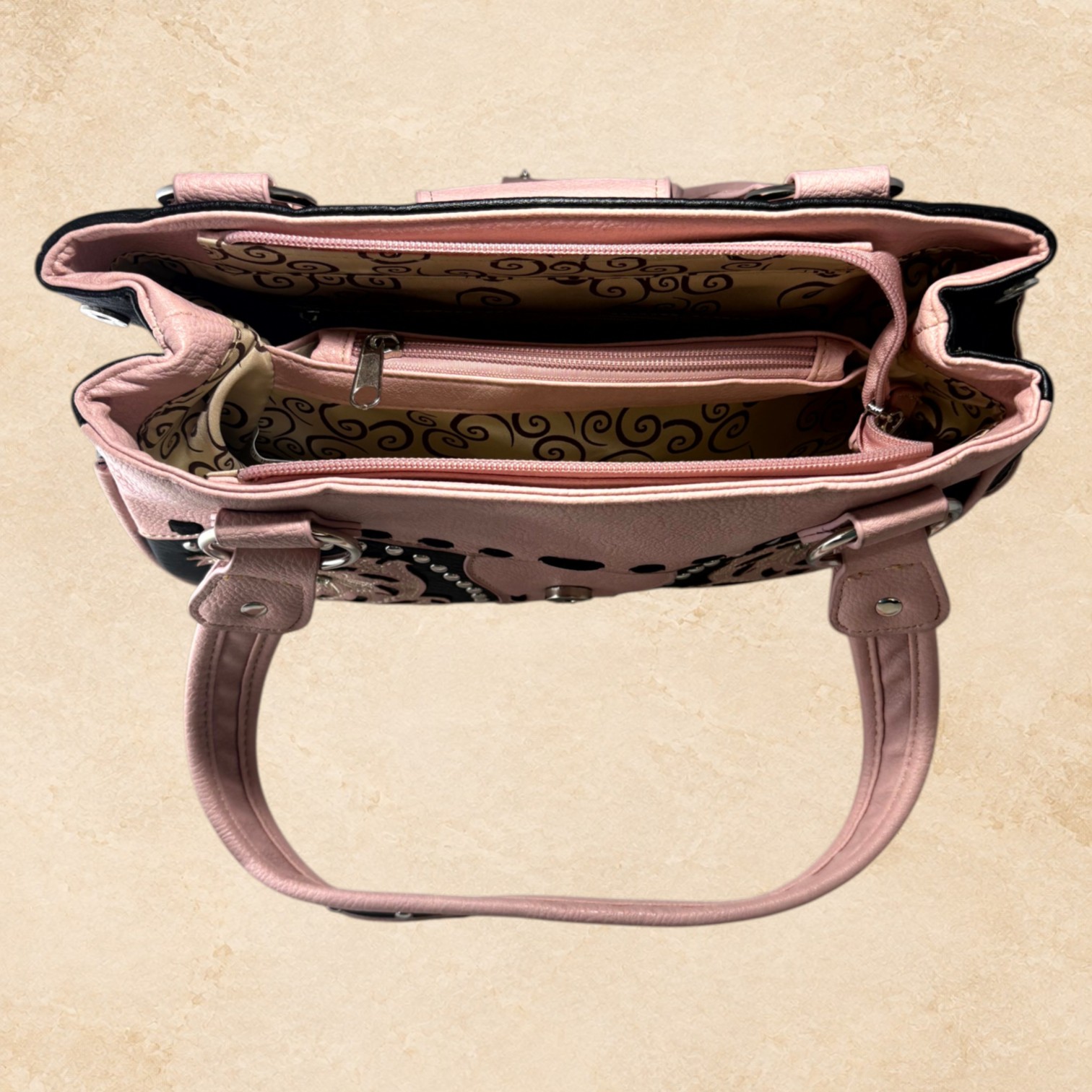 Blush pink and black purse with floral detailing, silver-tone studs, decorative stitching, and an ornate buckle accent.