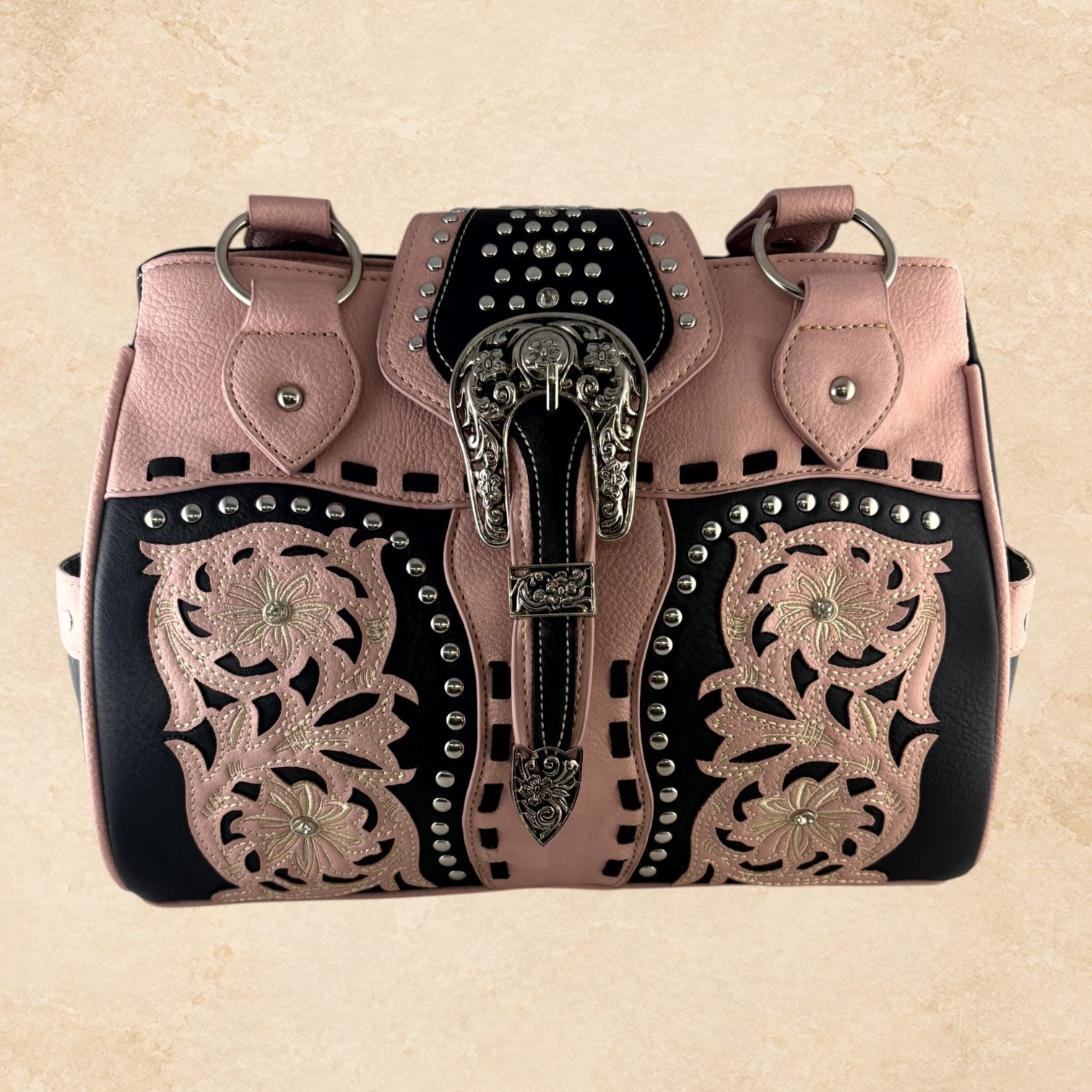 Blush pink and black purse with floral detailing, silver-tone studs, decorative stitching, and an ornate buckle accent.