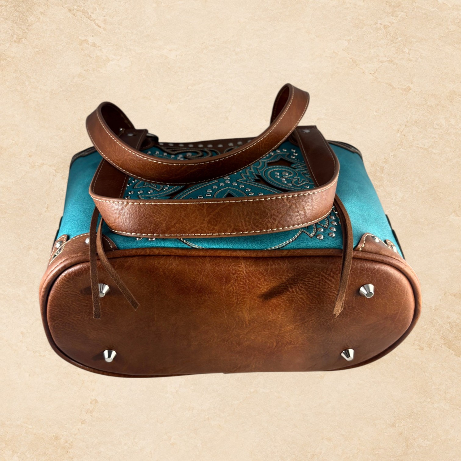 Turquoise and brown purse with intricate Southwestern detailing, silver-tone studs, decorative stitching, and brown leather-look accents.