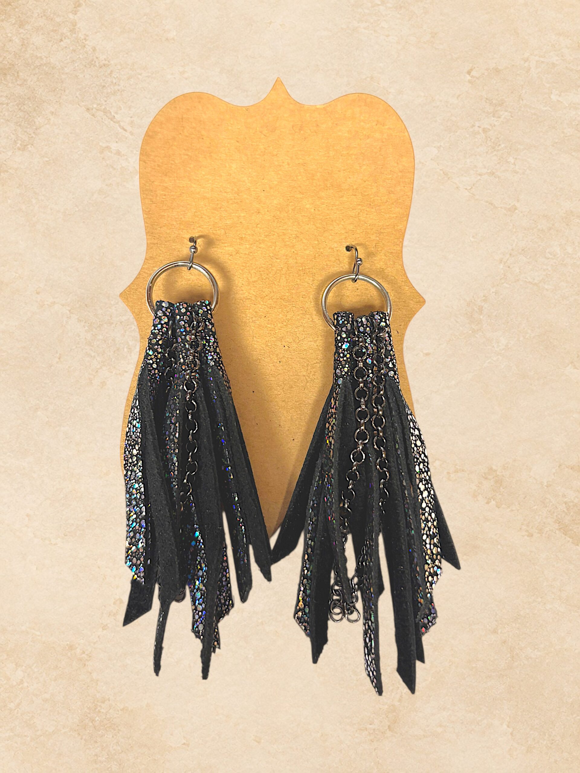 Black fringe earrings with shimmering metallic accents, chain details, and silver-tone hoops.